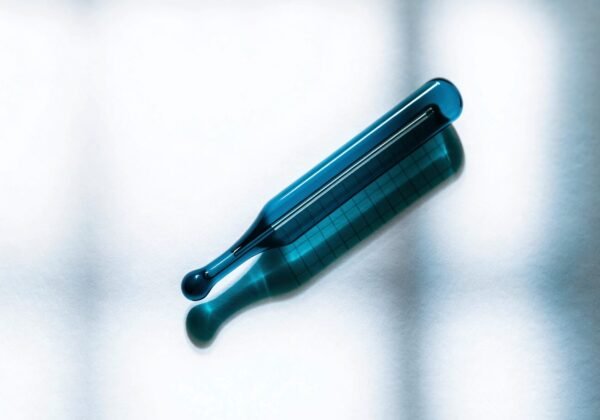 A glass clinical thermometer lying at an angle on gridded temperature-chart paper in soft daylight