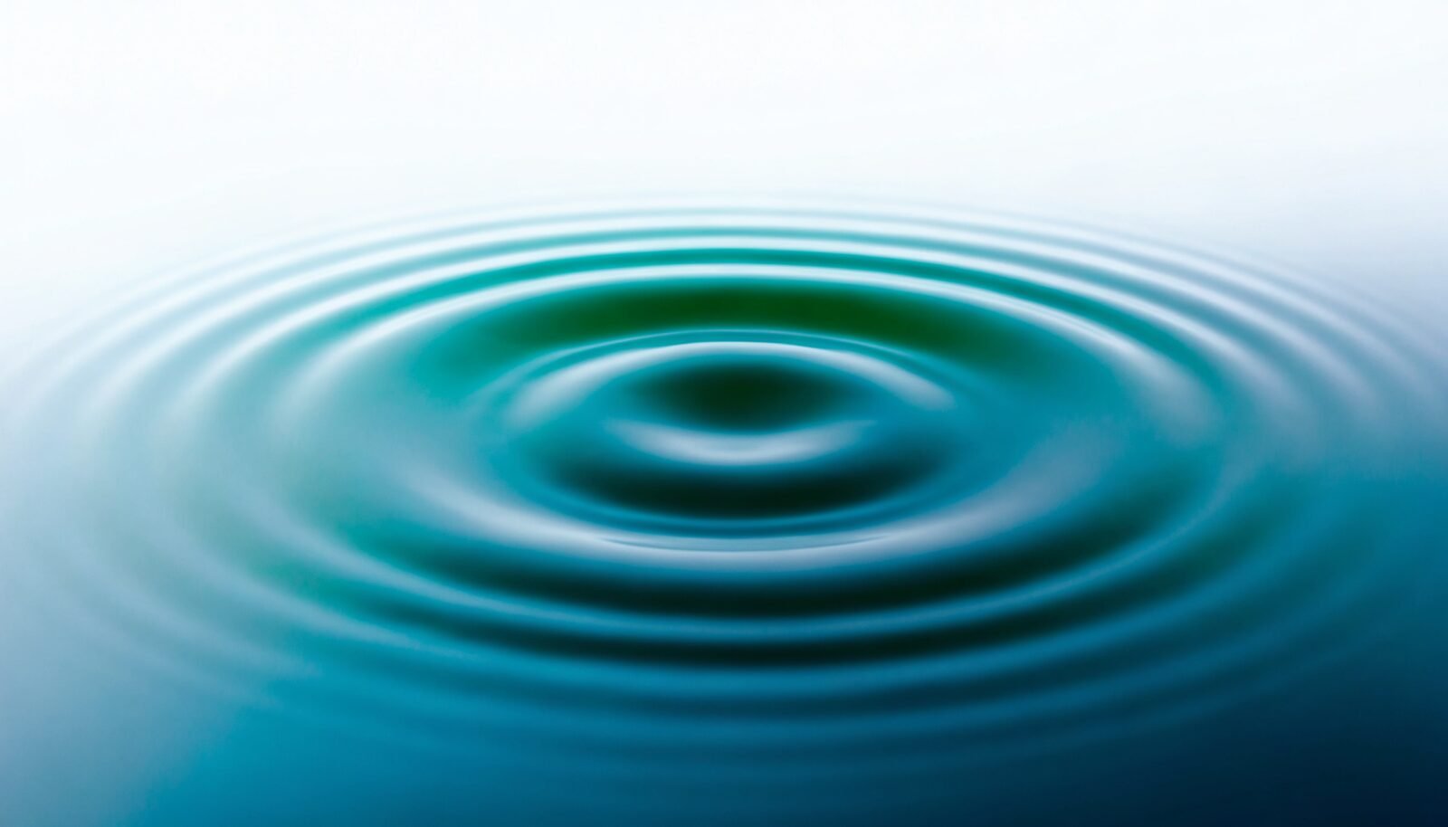 Concentric ripple rings spreading outward across a still pale blue surface
